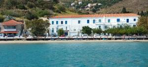 a white building on a beach next to the water at Roula's Suites in Andros