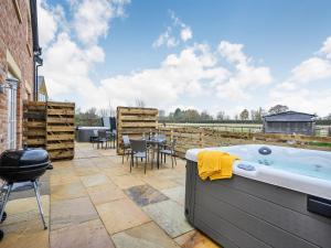 a hot tub on a patio with a table and chairs at Daisy Cottage - Uk38683 in Oxhill