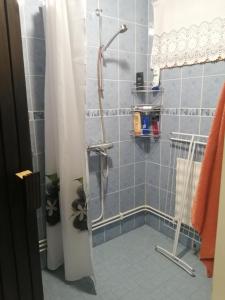 um chuveiro numa casa de banho com azulejos azuis e uma cortina de chuveiro em Rivitalokaksio Jäppilässä em Jäppilä