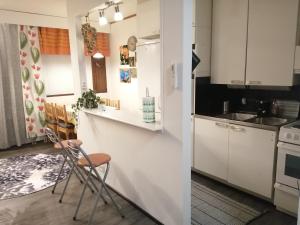 a kitchen with white cabinets and a counter and chairs at Rivitalokaksio Jäppilässä in Jäppilä