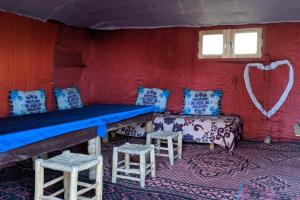 a room with a bench and stools in a room at Camel Trek Bivouac in Merzouga