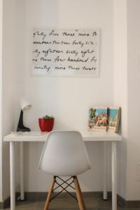 a white desk with a chair and a writing on the wall at B&B Benvenuti al Nord in Borgomanero