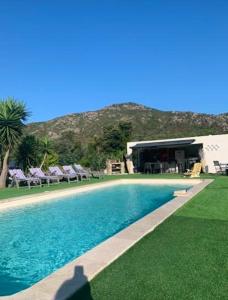 a swimming pool with lawn chairs and a building at Villa avec piscine à Saint-Florent - 350 m² vue mer et montagne in Saint-Florent