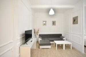 a white living room with a couch and a tv at Otilia in Bucharest