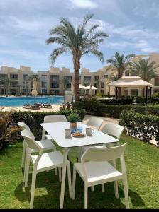 einen weißen Tisch und Stühle im Garten mit Pool in der Unterkunft Mangroovy - Buena Vista Pool and Marina views in Hurghada