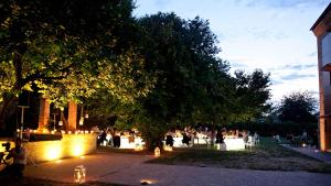 un groupe de personnes debout sous un arbre avec des lumières dans l'établissement Principessa Pio, à Ferrare