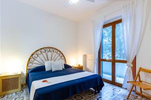 ein Schlafzimmer mit einem blauen Bett und einem großen Fenster in der Unterkunft Appartamento La Poesia Bilo 2 - MyHo Casa in Tortoreto Lido
