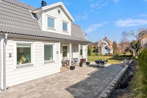 Cette maison blanche dispose d'une terrasse et d'une table. dans l'établissement Modernt hus med parkeringsplatser och trädgård, à Göteborg