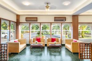 uma sala de estar com sofás, mesas e janelas em Holiday Resort & Spa A Unit of S Poddar Group em Gandhidham