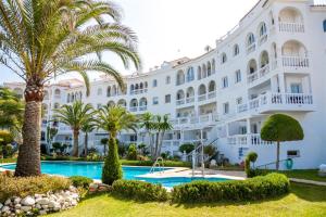 a large white building with palm trees and a swimming pool at Stella Maris B4 3A Nerja in Nerja