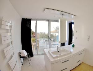 a white bathroom with a sink and a mirror at Les Digues Vauban in Ciboure