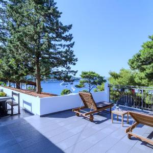 a patio with chairs and tables and a view of the water at Apartments Ammos in Saplunara