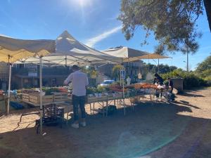 un hombre parado frente a un mercado de frutas y hortalizas en Version Lodge en Porto Vecchio