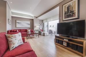 a living room with a red couch and a flat screen tv at Luxury Acropolis View Duplex Penthouse in Thiseio 155m2 in Athens