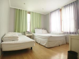 twee bedden in een kamer met groene gordijnen bij Hotel Good Inn in Seogwipo +37 foto's