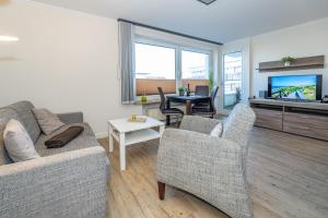 een woonkamer met een bank, stoelen en een televisie bij Beachlife in Westerland