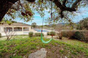 Eine grüne Schaukel hängt von einem Baum im Hof in der Unterkunft Superbe Appartement avec Piscine in Plan-de-la-Tour