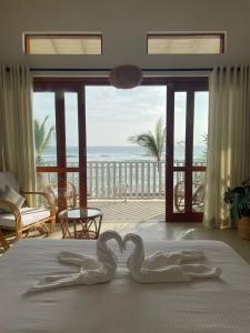 zwei Schwäne machen ein Herz auf einem Bett in einem Zimmer mit dem Meer in der Unterkunft Lihinya Beach Villa Ahangama in Ahangama