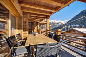a wooden table and chairs on a balcony with mountains at Chalet Larchwood by Mrs Miggins in Grimentz