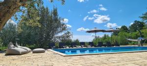 a swimming pool with lounge chairs and umbrellas at Spacious villa with pool, indoor jacuzzi and sauna near Poreč in Višnjan