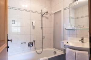 a bathroom with a shower and a tub and a sink at Hotel Rotlechhof in Berwang