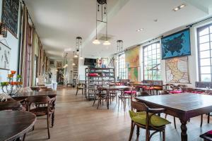 a restaurant with tables and chairs in a room with windows at Hotel De Pupiter in Kluisbergen