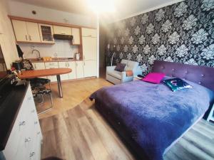 a bedroom with a purple bed and a kitchen at Apartament Klonowa in Kołobrzeg