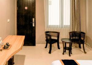 Zimmer mit 2 Stühlen, einem Tisch und einer Tür in der Unterkunft Class Premium Guest House in Kasri