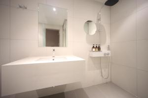 uma casa de banho branca com um lavatório e um espelho em Hound Hotel Junggwan em Busan
