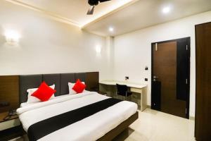 a bedroom with a bed with red pillows and a desk at Hotel Nikhil Regency in Bhilai