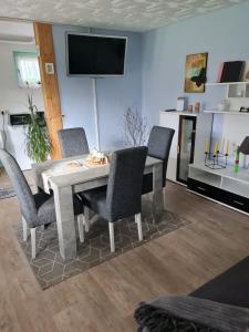 mesa de comedor con sillas y TV en la pared en Haus am Waldesrand, en Tanne