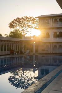 un edificio con piscina frente a la puesta de sol en Holiday Resort & Spa A Unit of S Poddar Group, en Gandhidham