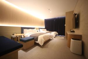 釜山にあるHound Hotel Junggwanのベッド2台とテレビが備わるホテルルームです。