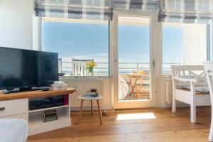 Sala de estar con TV y vistas al océano en Vier-Jahreszeiten-Haus-I-Wohnung-68, en Großenbrode