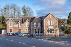 a large brick building with cars parked in front of it at The Woodside in Doune