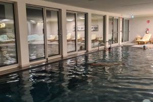 a person swimming in a pool in a building at Luxury apartment with pool, sauna, SPA in Champoluc