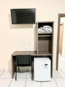 a computer desk with a television and a chair at HOTEL SAYMON in Cafelândia