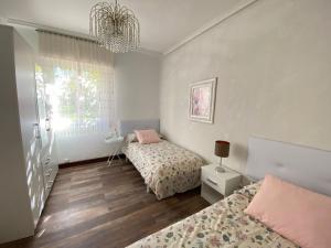 a bedroom with two beds and a chandelier at Bajo con terraza a 5 min de la playa (3 hab-6 per) in Santander