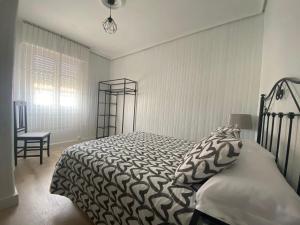1 dormitorio con 1 cama, 1 silla y 1 ventana en Bajo con terraza a 5 min de la playa (3 hab-6 per) en Santander