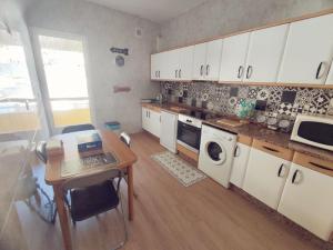 a kitchen with white cabinets and a table with a laptop at Quiroga centro paradise in Quiroga