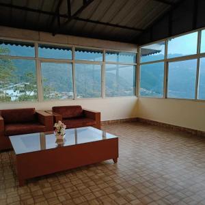 a living room with couches and a table and windows at Hotel Royal Gangtok in Gangtok