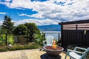 a patio with a fire pit and two chairs at Stunning Lake View w Private Hot tub, Pool -snl & Outdoor Kitchen 2400sqft in West Kelowna