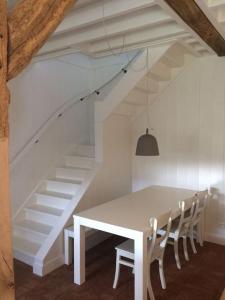 uma mesa de jantar branca com cadeiras e uma escada em Ottenstein em Hierden