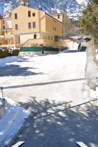 羅卡迪坎比奧的住宿－Appartamento Residence Monte D'Ocre，一条有雪覆盖的街道,有建筑背景