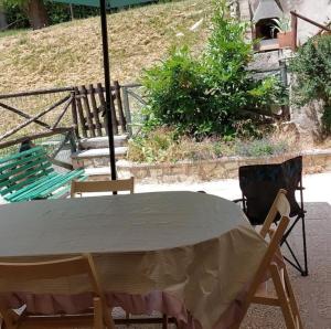 stół z 2 krzesłami i parasolem w obiekcie Appartamento Residence Monte D'Ocre w mieście Rocca di Cambio