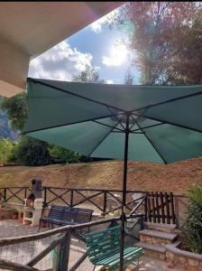 a green umbrella on a patio with two chairs at Appartamento Residence Monte D'Ocre in Rocca di Cambio