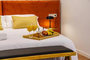a tray of fruit on a bed with glasses of orange juice at SUNSET MALAGA Exclusive Alameda in Málaga