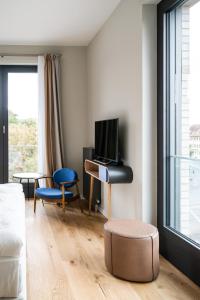 a living room with a tv and a couch and a chair at FREIgeist Göttingen Innenstadt, A Member of Design Hotels in Göttingen
