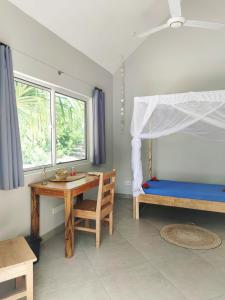 1 dormitorio con escritorio, 1 cama y 1 mesa en Princess of Zanzibar, en Michamvi
