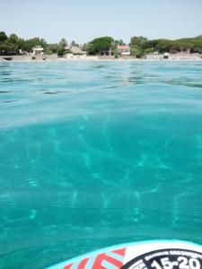 uma piscina de água azul com uma praia ao fundo em Casa al Mare con Giardino Privato em SantʼAndrea